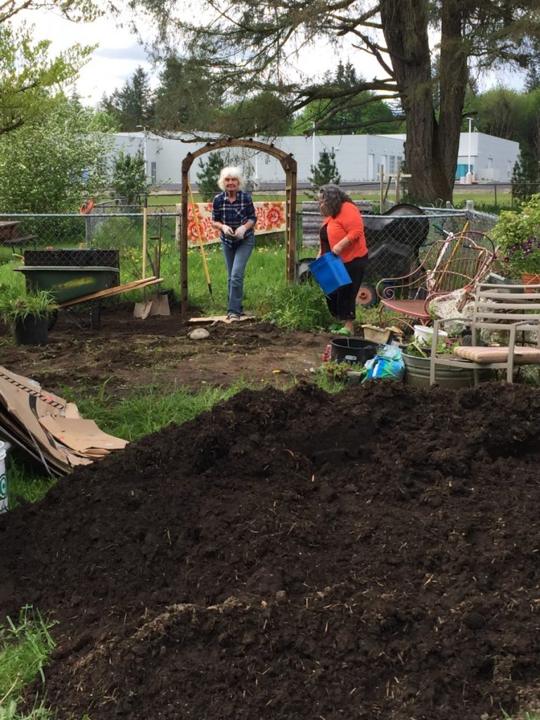 The garden recipient, left, and one of the volunteer builders preparing the space where the beds were to be placed. In the foreground is the pile of soil, delivered earlier in the week, that we moved to the beds, one wheelbarrow at a time!