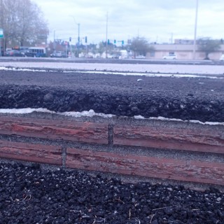 the brick foundation of an old building covered in asphalt, one of the few parts of the structure that are still there