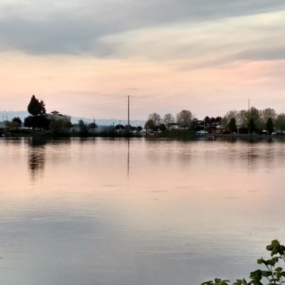 Lake reflecting sunset with buildings in the distance