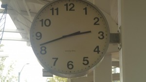 This is an extreme close up of a clock hanging from a concrete column. This photo is an ambiguous space composition with an realistic and expressionistic style because it not only shows the present time, but it also represents what was in the past as well. 