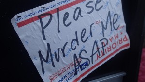 close-up of USPS shipping sticker with the words "Please Murder Me ASAP"