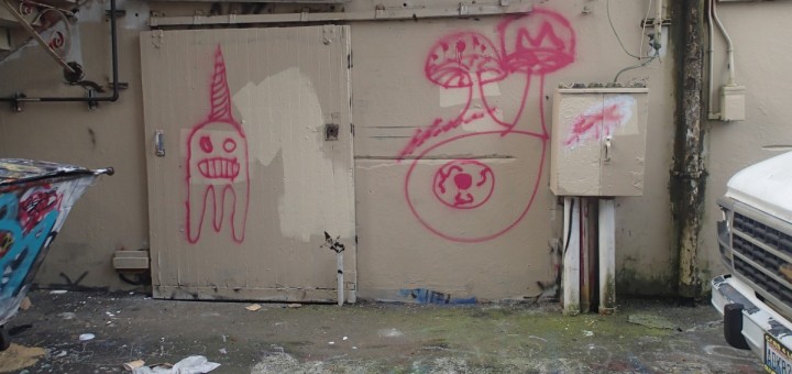 small section of alleyway with childlike graffiti of ghost wearing party hat, and spotted mushrooms
