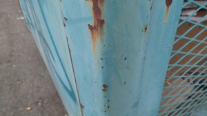 The corner of a robins-egg-blue pole with speckles of rust.